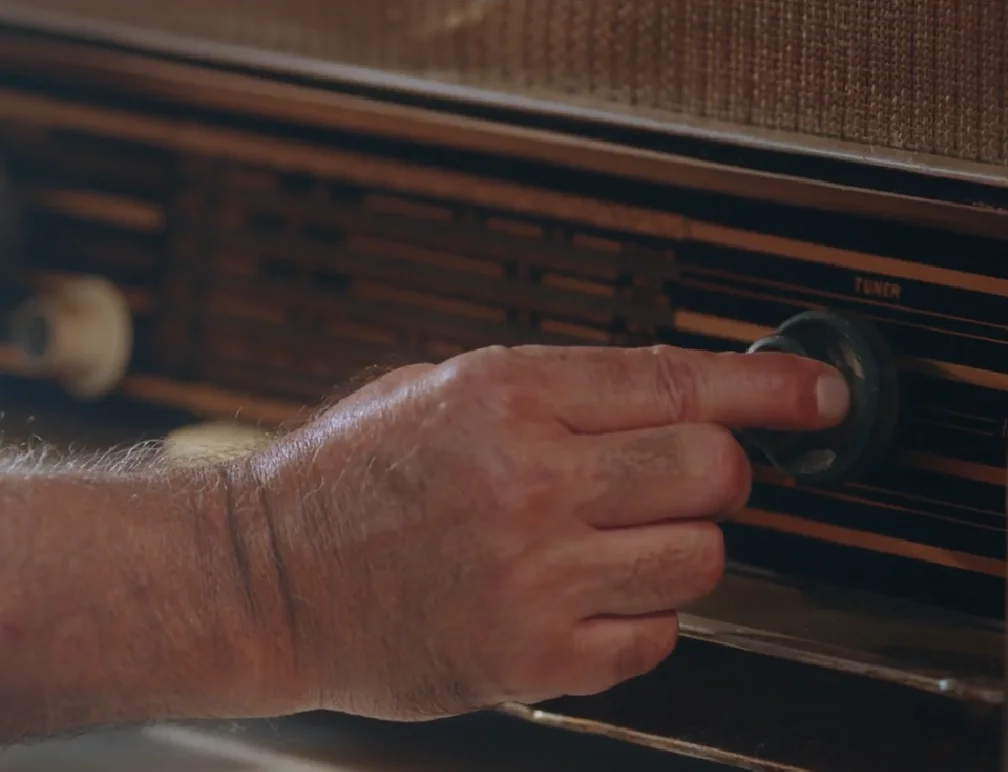 A hand is tuning an old radio